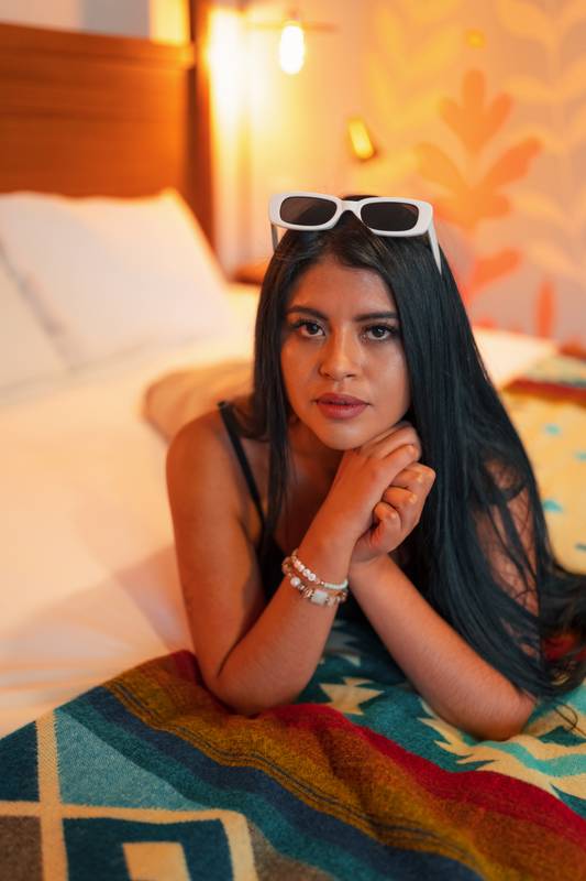 lying on a bed a young woman with black hair and makeup, model