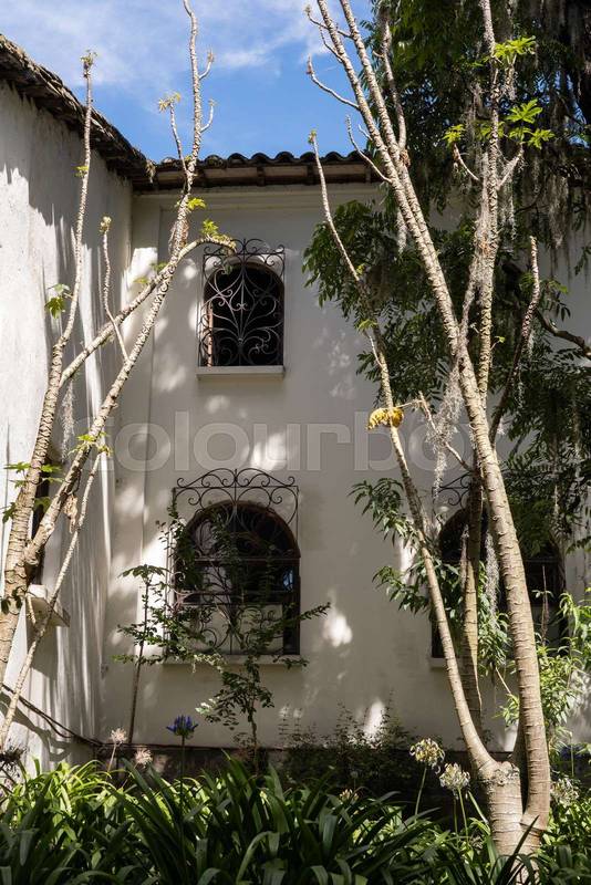 clay tiled roof, white colonial columns, and lush countryside vegetation.