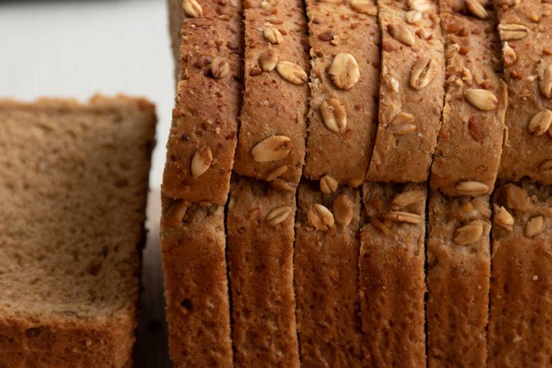 sliced wholemeal bread pan with oatmeal on top, portioned healthy food