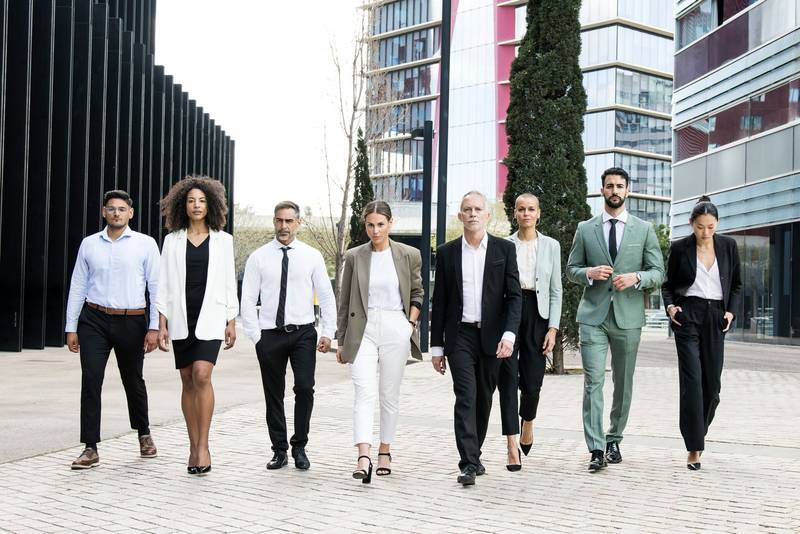 Group of confident business people walking the street together looking at camera. Diverse team of successful businesswoman and businessman walking outside.