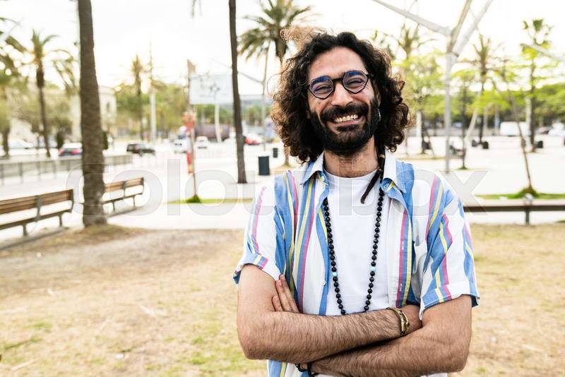 Portrait of happy hipster guy smiling wearing a shirt looking at camera and taking a selfie in the street. Carefree cheerful stylish male wearing glasses confident and satisfied standing outside 