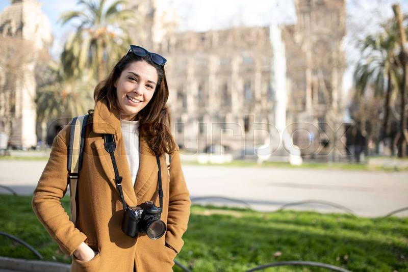 Smiling young female photographer on city street