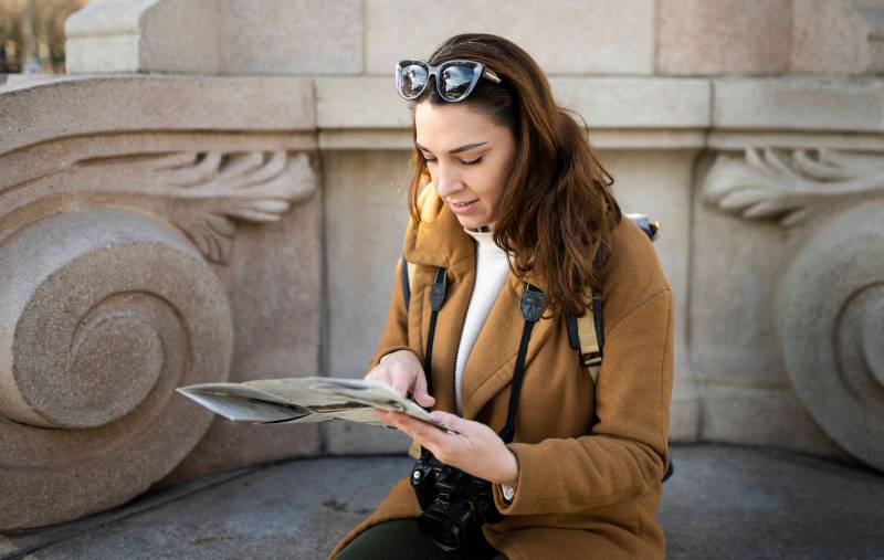 happy traveller woman looking a map outdoors. cheerful young female on vacations.