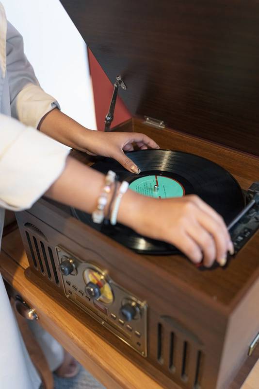 hands placing music on a turntable with vintage design