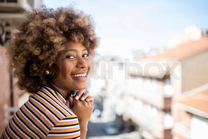 portrait of young smiling woman looking at camera standing outdoors. Closeup of beautiful happy girl in the city with hands on chin. 