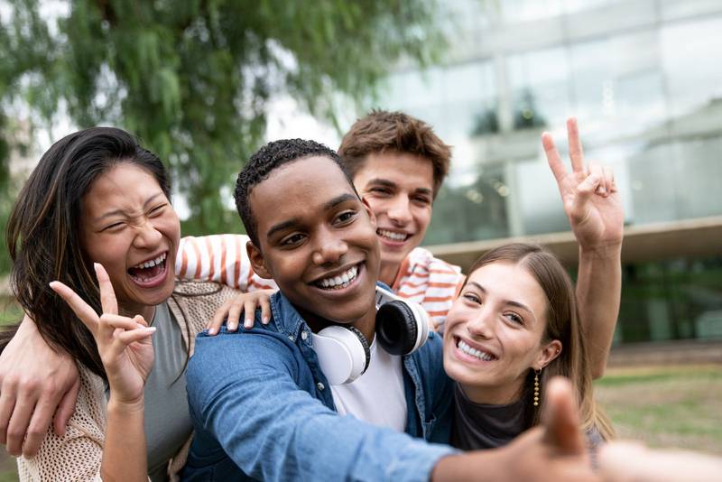 Cheerful group of friends taking a selfie laughing.Multiracial young people having fun and taking pictures outside.