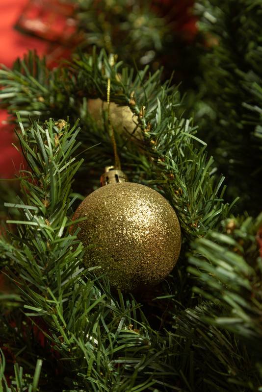 branch of an artificial pine decorated with a golden and frosted light bulb