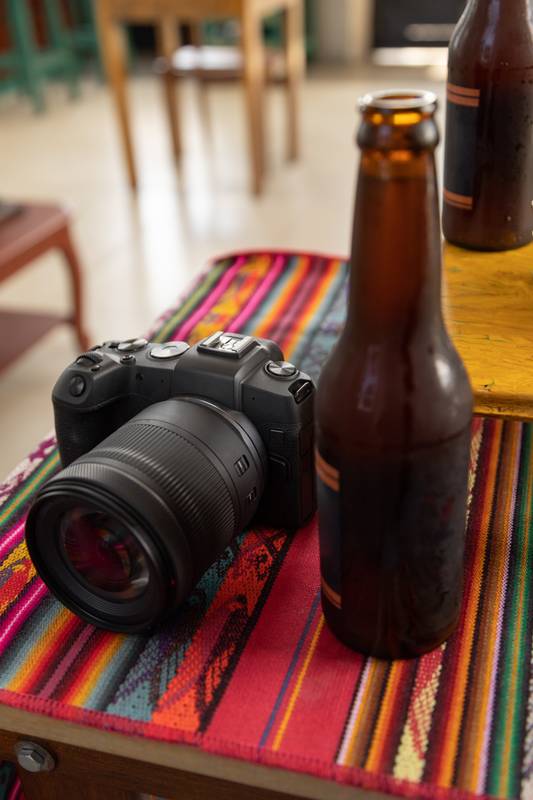colorful tablecloth with a digital professional camera next to a bottle of beer