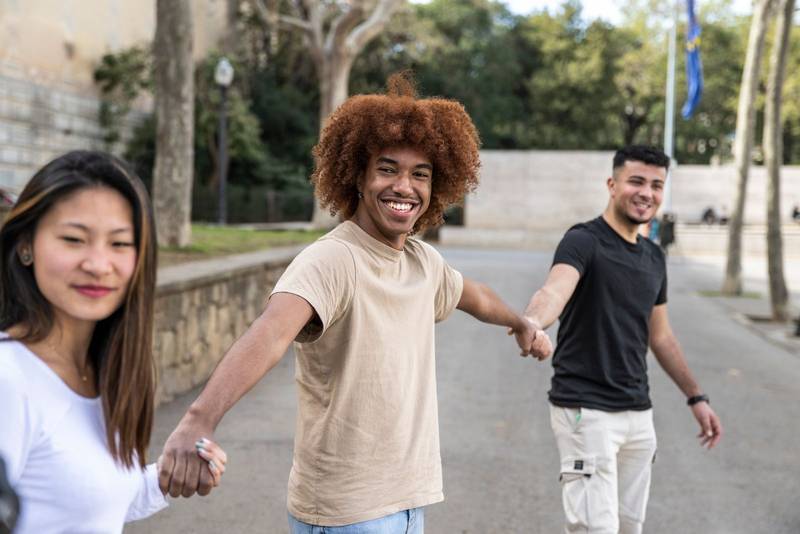 Three diverse and confident friends holding hands together. Multiracial group of people smiling and holding hands in a line.