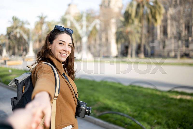 happy young woman tourist walking on the city and looking back - pov cheerful couple on holidays - travel, relaxation, friendship concept