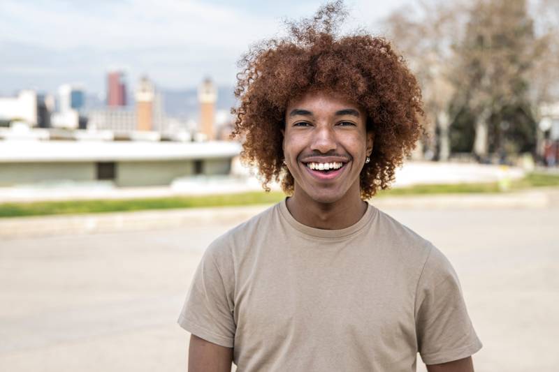 Young handsome guy smiling relaxed and looking at camera in the street. Confident happy man laughing and staring at camera standing outdoors.