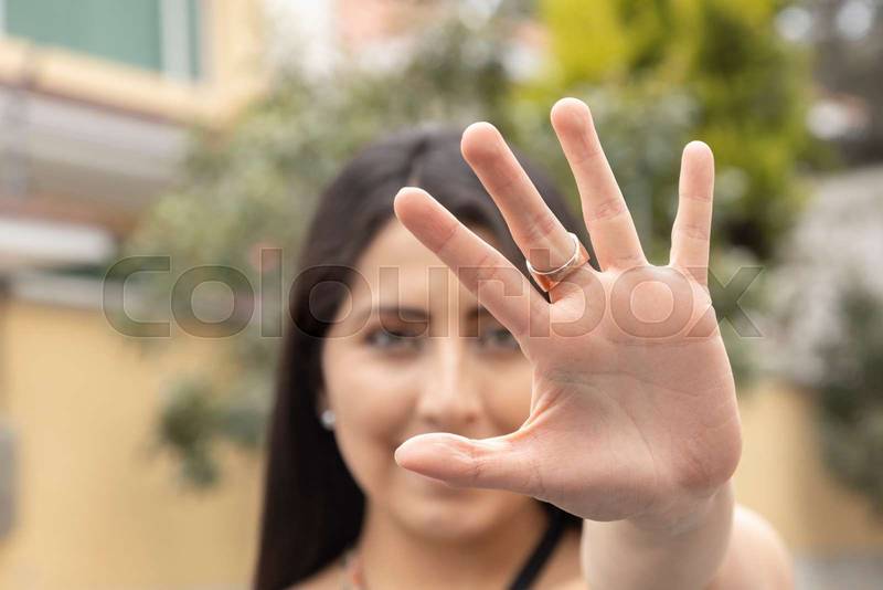 face of attractive young woman with her long black hair showing the palm of her hand
