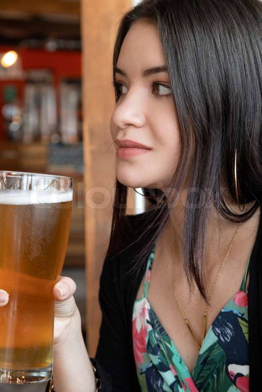 young beautiful woman holding a drink in a crystal glass, wearing jewelry